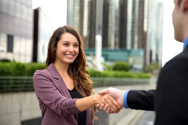 A sales person smiling after he was hired. A New Home Sales Consultant shaking hands with a homebuyer.