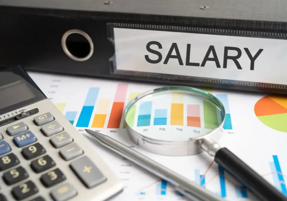 A salary binder and compensation charts on a desk